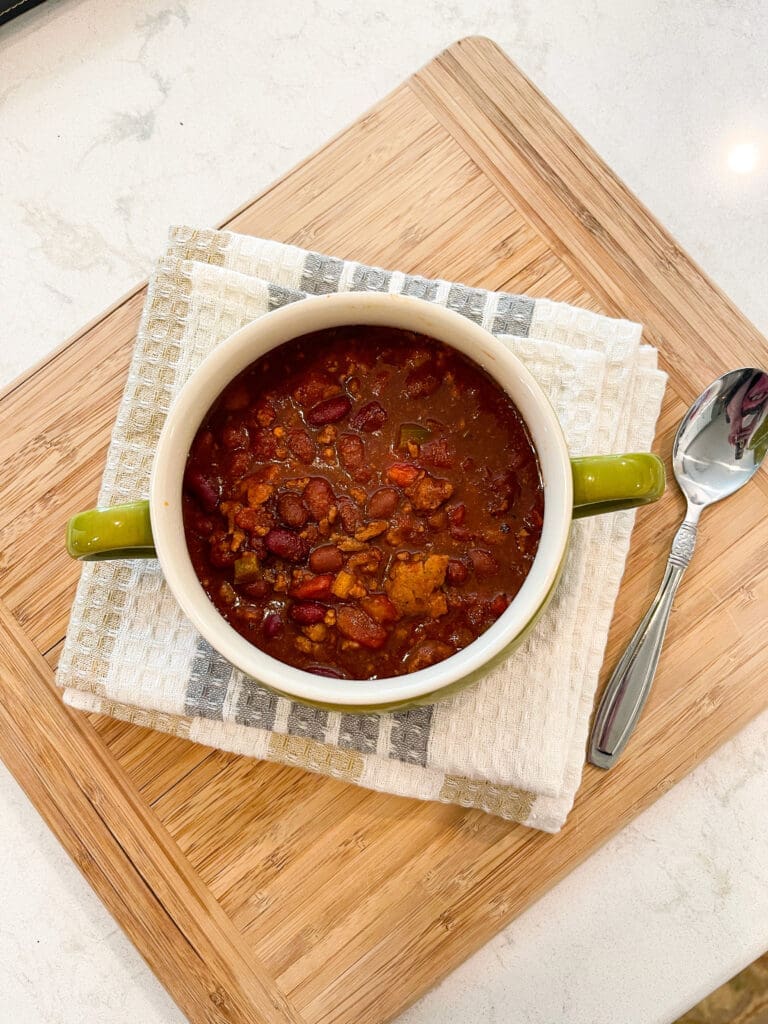 Finished bowl of easy crockpot homemade chili served in a green crock with a spoon, ready to enjoy.